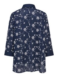 Tumši zils krekls ar garām piedurknēm un baltu ziedu izšuvumu, ar klasisku apkakli un pogas uz manžetēm, redzams no aizmugures.