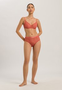 Rød lingeri sæt med en blonde bralette med justerbare stropper og højhævede trusser, der viser indviklede geometriske mønstre.