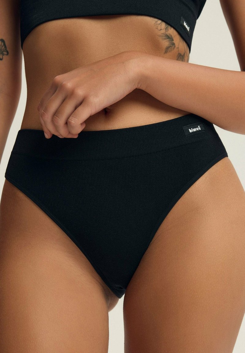 Czarne ribbed bawełniane majtki bikini z szerokim pasem. Na przodzie znajduje się mała metka marki. Materiał ma gładką teksturę.