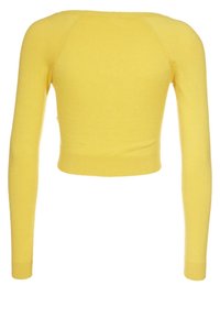 Gul kortärmad tröja med långa ärmar, ribbade muddar och en slät, mjuk textur. Halsringningen är rundad och tyget verkar vara lätt. 