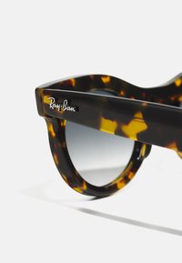 Pyöreät aurinkolasit, joissa on kilpikonnakuorikehys, harmaasävytetty musta linssi ja näyttävä Ray-Ban-logo sivulla. Kiiltävä pinta ja sileä rakenne.
