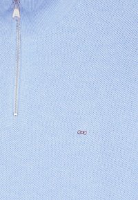 Pull en maille bleu clair, à col zippé avec une petite touche de logo rose sur le côté gauche. Il dispose d'une fermeture éclair lisse et d'un col côtelé.