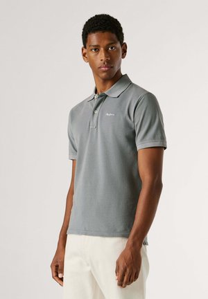 Šedé polo tričko s klasickým límečkem, dvěma knoflíky a krátkými rukávy, s nenápadným logem na hrudi. Materiál je hladký a texturovaný.