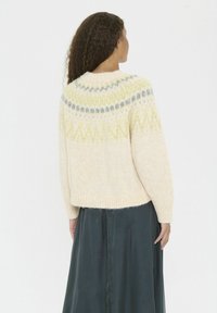 Pulover crem tricotat cu guler rotund, cu modele multicolore în galben și gri. Material moale din lână texturată, cu tiv cu dungi.