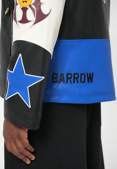 Schwarze und weiße Lederjacke mit blauen Akzenten. Mit gesticktem Stern und dem Text "BARROW". Glatte Textur mit modernem Design.