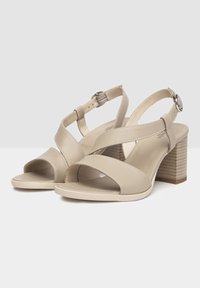 Beige Leder-Sandalen mit einem überkreuzten Riemendesign, offenem Zeh, verstellbarem Knöchelriemen und einem Blockabsatz mit strukturiertem Holzdesign.