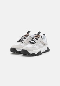 Debelušne superge z belim in sivim zgornjim delom iz semiša in mrežice, črnimi vezalkami, detajli logotipa ter debelim črnim teksturiranim podplatom.