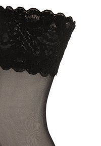Sorte blonde strømpebukser med et blomster mønster, der har en gennemsigtig, glat tekstur langs benet og en bølget kant foroven.