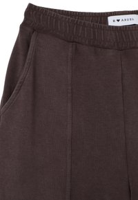 Pantalones de chándal color marrón oscuro con una cinturilla elástica, bolsillos laterales y una tela lisa y texturizada. Etiqueta de la marca visible en la cintura.