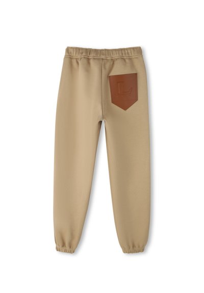 Beige sweatpants met een elastische tailleband, taps toelopende boorden en een bruine leren patch op de achterkant van de zak met een logo.