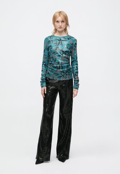 Haut à manches longues turquoise avec un motif floral et des sequins associé à un pantalon large en sequins noirs. Tissu lisse avec une texture brillante.
