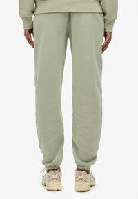 Miętowe dresy z tapered cuffs, charakteryzujące się miękką teksturą i elastycznym paskiem w talii, połączone z beżowymi sneakersami.