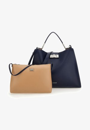 Große marineblaue Handtasche mit oberem Griff und silberner Schnalle neben einer kleineren hellbraunen Umhängetasche mit Reißverschluss und verstellbarem Gurt.