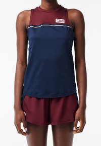 Marinblå ärmlös sporttopp med vinröda detaljer och en logotyp, kombinerad med vinröda shorts med sidofickor och avslappnad passform.