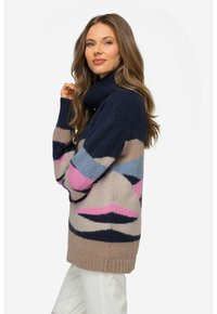 Pull en tricot avec un col montant, présentant des motifs géométriques en bleu marine, beige, rose et bleu. Texture douce et ourlet côtelé.