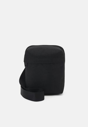 Borsa compatta a tracolla nera con tasca frontale con cerniera e tracolla regolabile, su sfondo chiaro uniforme.