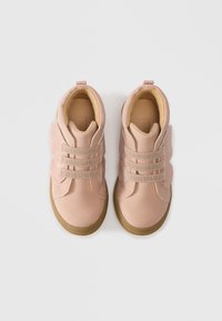 Růžové dětské tenisky s kulatými špičkami, texturovanými bočními panely a třpytivými elastickými pásky. Hnědé stélky a gumové podrážky.