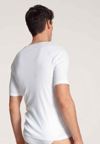 Weißes T-Shirt mit kurzen Ärmeln und rundem Halsauschnitt, mit glatter Textur und taillierter Form. Der Stoff wirkt weich und leicht.