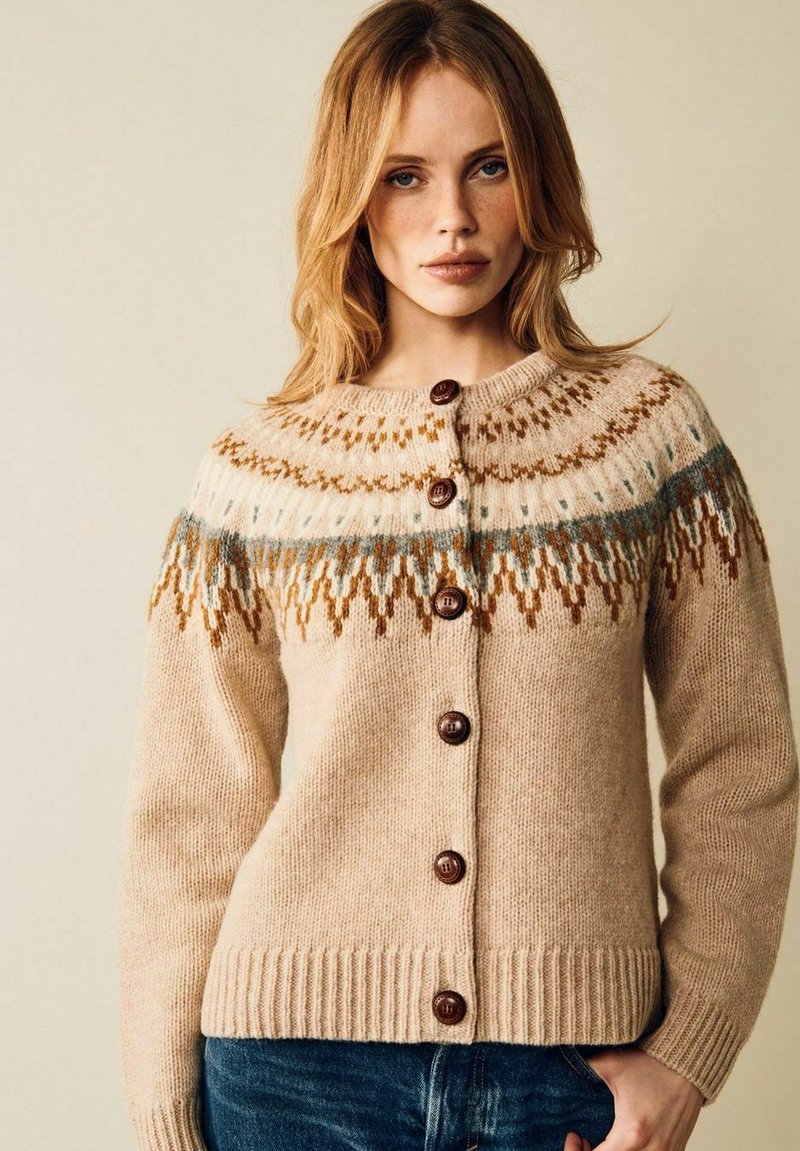Beige stickad cardigan med rund halsringning, med en mönstrad okdel i brunt och blått, och träknappar fram. Ribbad nederkant.