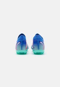 Scarpe da calcio blu con un design a gradiente, caratterizzate da una tomaia in mesh testurizzato, suola turchese e un logo evidente con accenti rosa e bianchi.