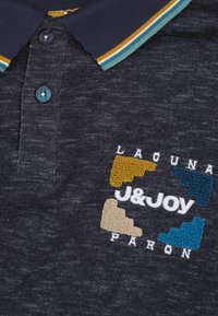 Marine polo shirt van een textuurstof. Kenmerkt zich door een contrasterende kraag met gele, teal en witte strepen. Borduurdesign met een levendig gekleurd logo.