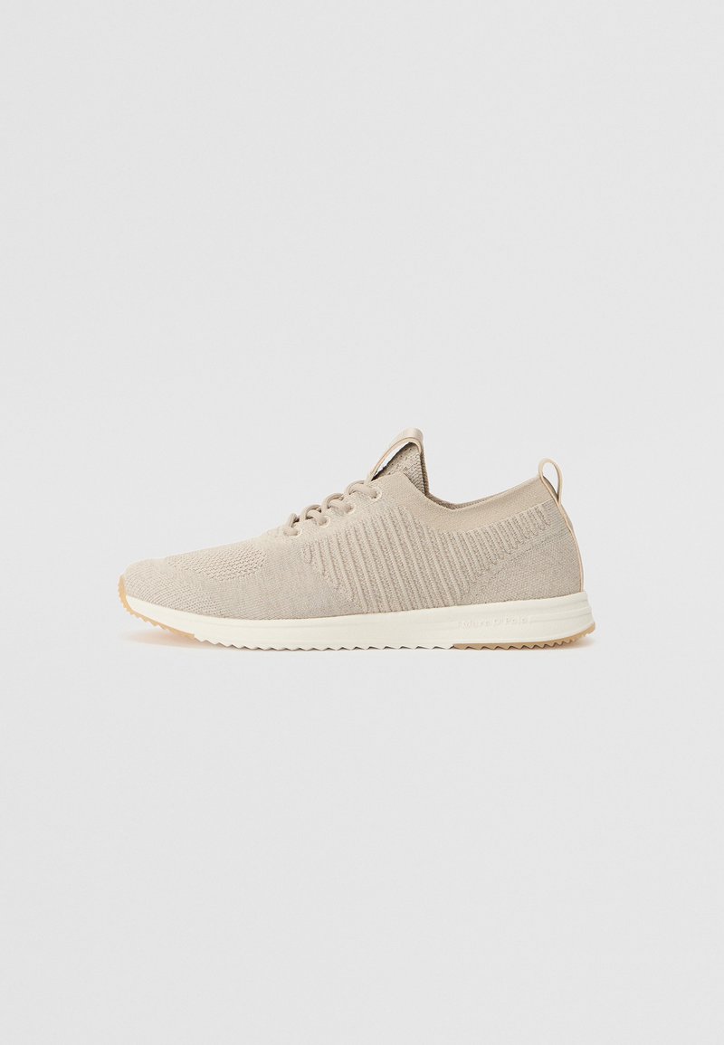 Helle beige Strick-Sneakers mit strukturiertem Obermaterial, weißer Sohle und Schlaufe hinten. Besitzt dezente Rippendetails an den Seiten.