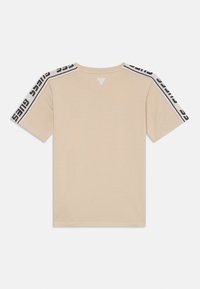 Beige t-shirt met korte mouwen met zwarte logotape op de schouders, driehoekig rugdetail en een klassiek crewneck ontwerp.
