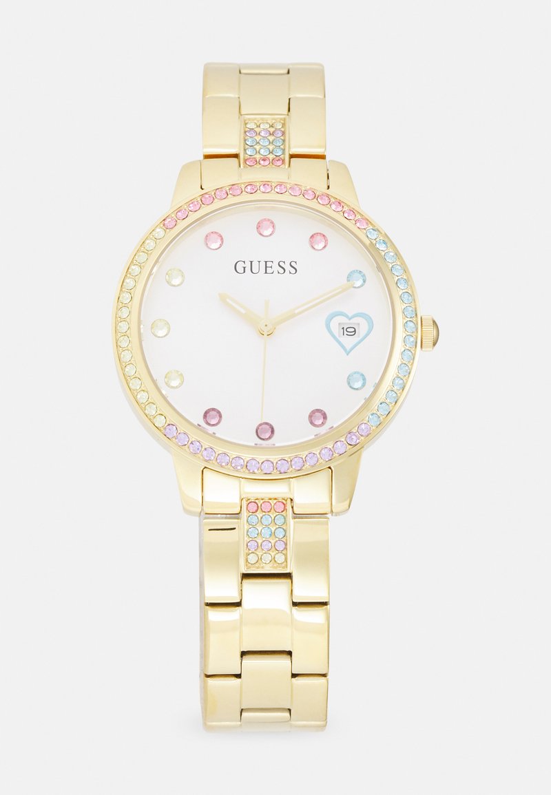 Gold metal watch with a white dial, studded with colorful crystals on the bezel and bracelet. Features a heart-shaped date window.
