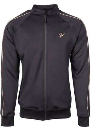 Veste noire zippée en tissu lisse, avec des accents dorés le long des épaules et des poches latérales avec des fermetures éclair.