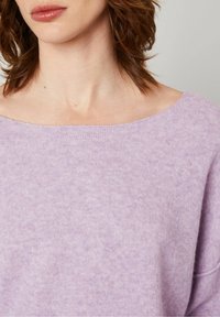 Lys lilla oversized sweater med en bred halsudskæring og blød, tekstureret stof med et subtilt meleret mønster.