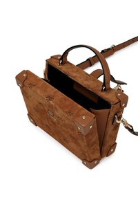 Brązowa torebka z zamszu o strukturalnym designie, z metalowymi akcentami w rogach, odczepianym paskiem i otwartym wierzchem odsłaniającym czarne wnętrze.