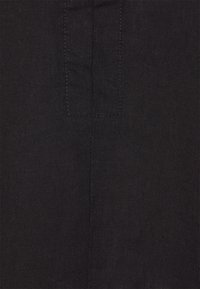 Tela de lino negra con una textura suave, con una costura visible y un pequeño parche rectangular de tela. Color uniforme en toda la superficie.