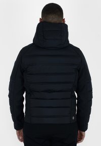 Giubbotto piumino nero con colletto alto, caratterizzato da pannelli trapuntati orizzontali e inserti in tessuto liscio sulle maniche e sui lati.