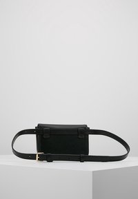 Bolso de cintura de cuero negro con forma rectangular, textura suave, correa ajustable, hebilla dorada y diseño minimalista.