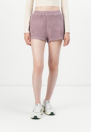 Paarse geruite shorts met een elastische tailleband, met een losse pasvorm en een gladde textuur. Draagt met lichtgekleurde sneakers.