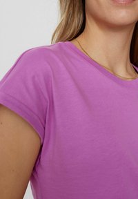 Paarse korte mouwen t-shirt met een ronde hals. De stof lijkt zacht met een subtiele textuur en een lichte glans.