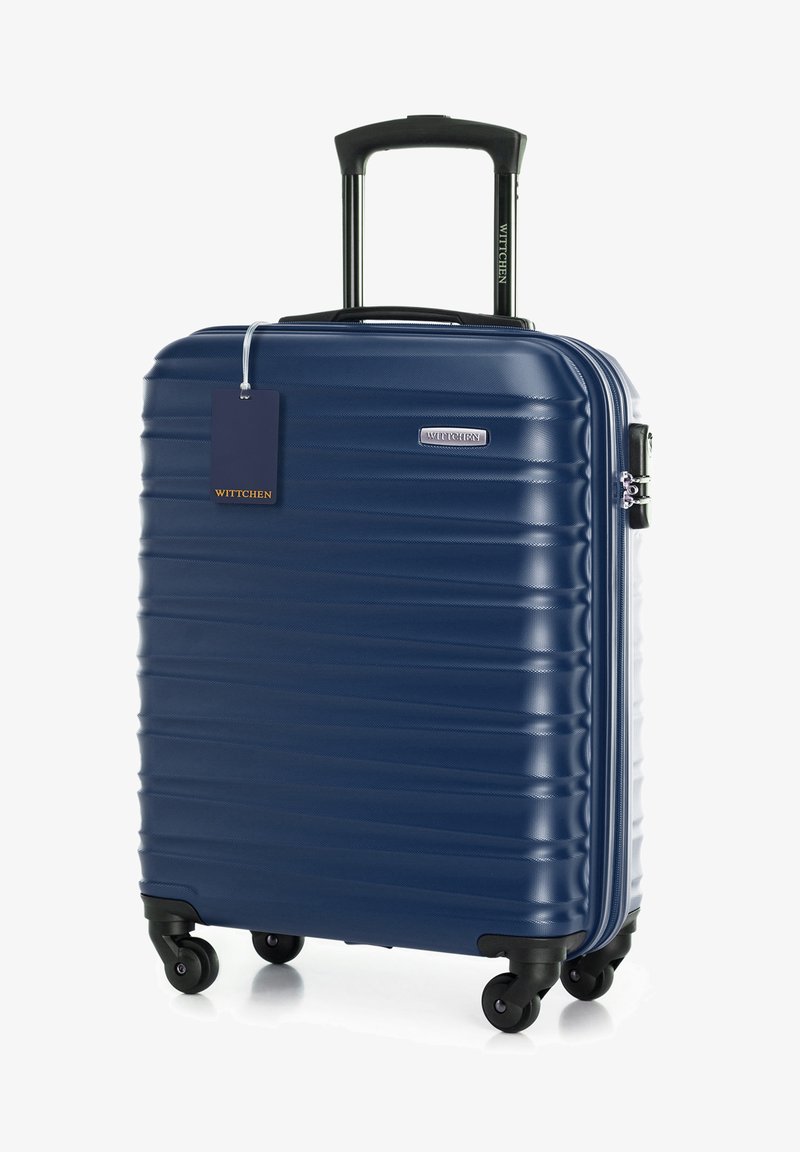 Námořnický tvrdý kufr s rýhovaným povrchem, teleskopickou rukojetí, čtyřmi černými kolečky a připojenou malou visačkou na zavazadlo.