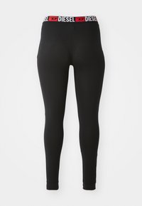 Leggings noirs au design ajusté, dotés d'une large ceinture avec des inscriptions "DIESEL" en rouge et blanc. Le tissu a l'air lisse et extensible.