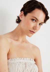 Strapless top met een geplooide textuur in lichtbeige strepen, met een gerimpelde elastische halslijn en zachte stof tegen de huid.