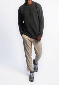 Donkergrijze sweatshirt met lange mouwen en een ronde hals, gecombineerd met lichtbeige broek en grijze sneakers. Gave textuur, casual fit.