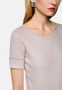Helles rosa Kurzarm-Oberteil mit rundem Ausschnitt, geripptem Material und aufgerollten Ärmelbündchen, das ein elegantes, minimalistisches Design betont.