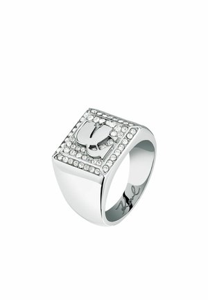 Silver-toned ring with a square face, featuring a raised design and surrounded by rhinestones. Smooth, shiny finish; engraved signature inside.