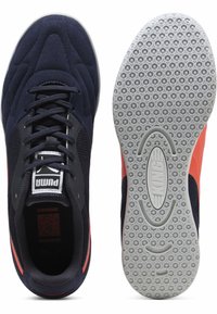 Zapatillas deportivas Puma, con un upper de ante y malla en azul marino, acentos rojos en contraste y una suela de goma gris texturizada.