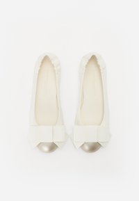 Ballerines blanches avec un dessus en tissu lisse, dotées d'un large nœud et d'un bout en métal doré. Bord élastiqué pour un maintien sécurisé.