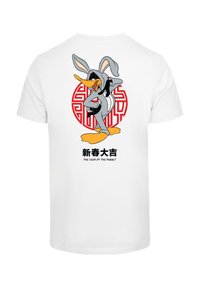 White cotton t-shirt featuring a graphic of a gray cartoon character wearing rabbit ears against a red circular pattern, with text below.