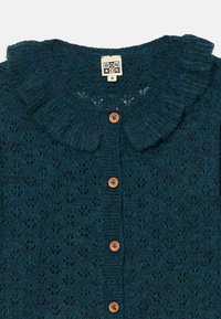 Cardigã tricotado em teal com colarinho franzido, apresentando uma textura decorativa e cinco botões de madeira na frente.