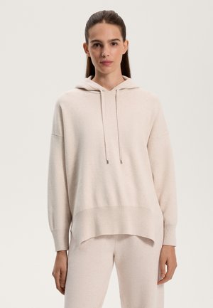 Light beige hooded sweatshirt with a loose fit, ribbed cuffs, and a hem that dips lower at the back. Soft texture, minimal design.