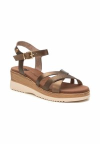 Sandalias de cuña marrones con diseño de tiras cruzadas en materiales lisos y texturizados, correa de tobillo ajustable y suela de goma de color claro.