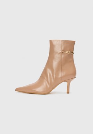 Beige nahka nilkkabooti, jossa on terävä kärki, kapea korko ja kultaketjuviimeistely. Tasainen pinta, jossa on minimaalinen ompellut yksityiskohta.