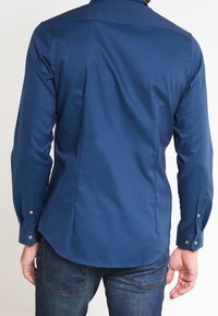 Donkerblauw overhemd met lange mouwen en een gladde textuur, voorzien van een standaardkraag, manchetten met knopen en een getailleerde pasvorm aan de achterkant.